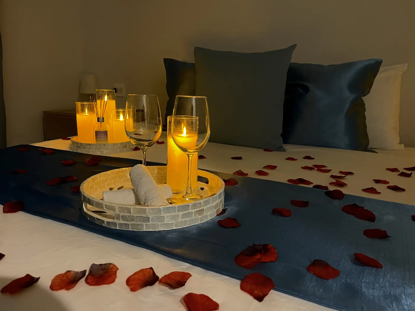 Chambre préparée pour une occasion romantique : pétales, bougies et plateau sur le lit